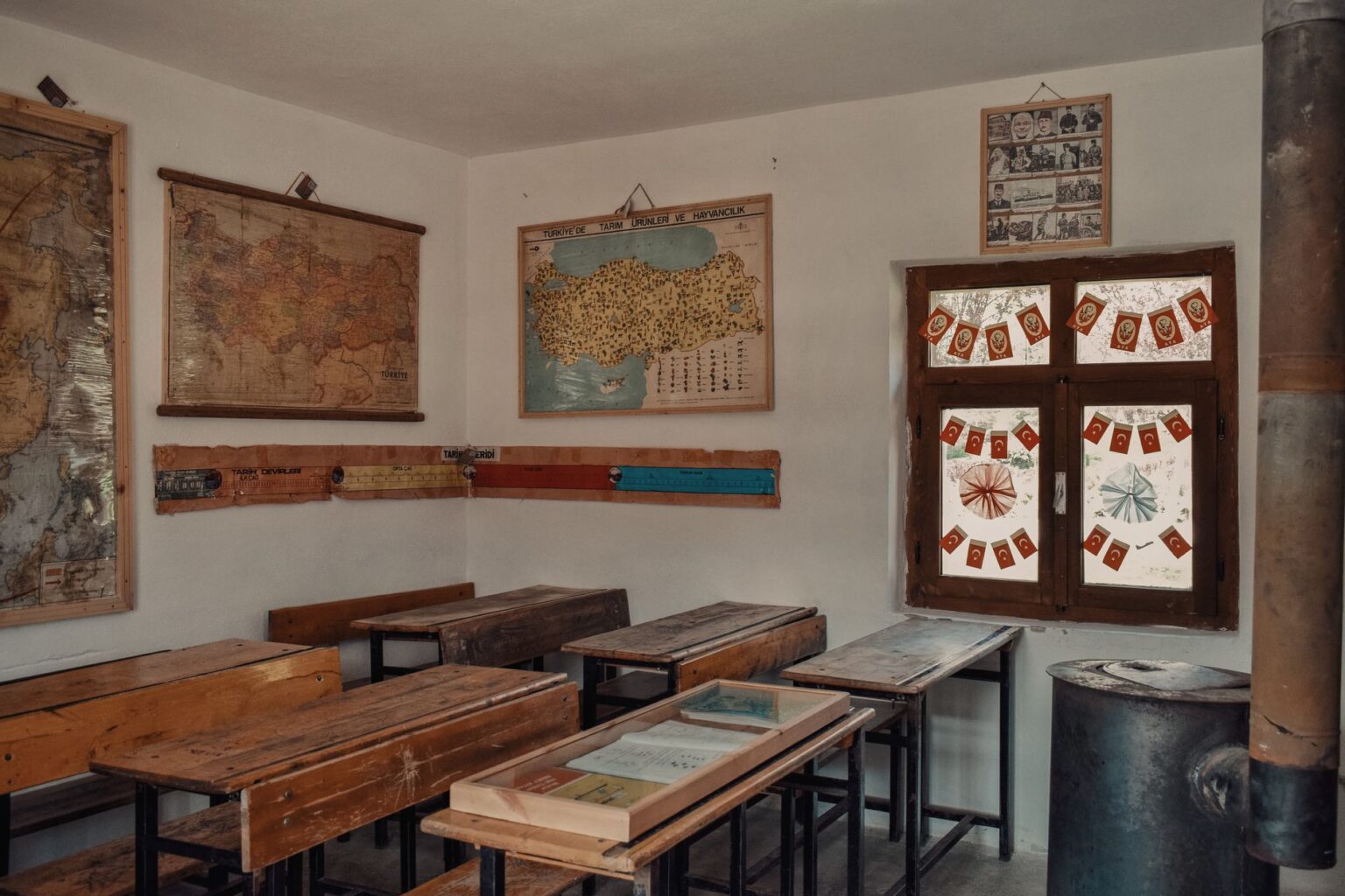 An old classroom with wooden desks and maps on the walls
