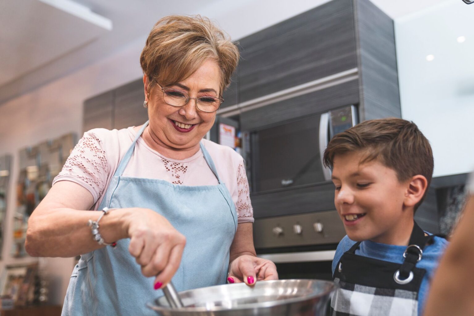 Ruth stirring a bowl in her kitchen while her grandson watches